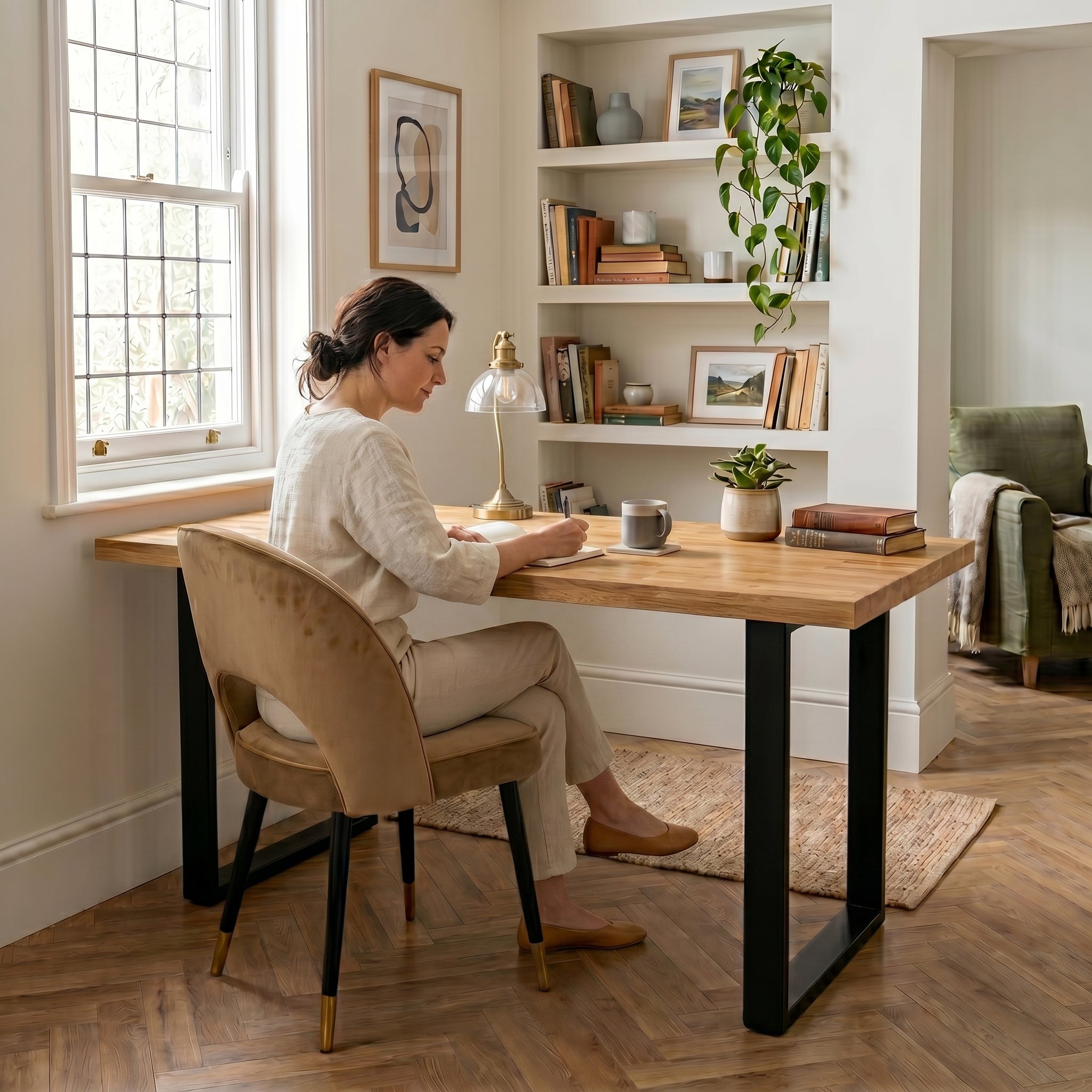 Woman sitting at a wooden desk in a home office with books and decor.
