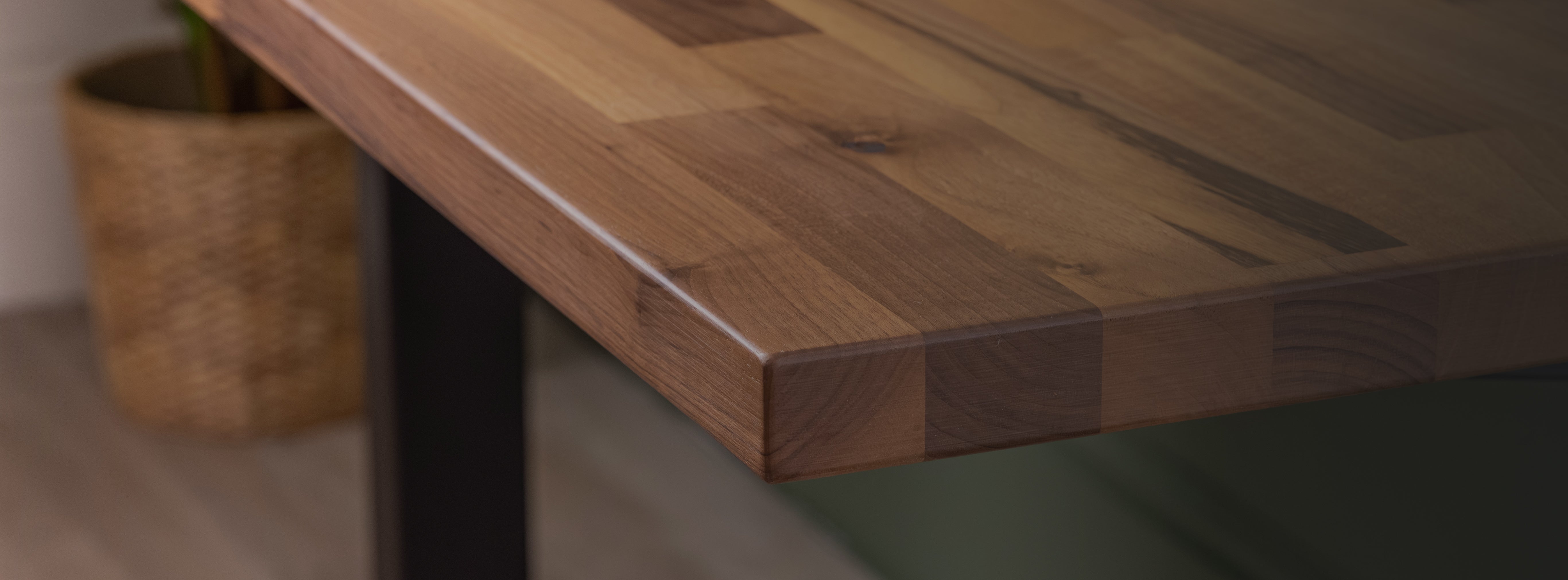 Close-up of a solid wood desktop corner, showing the natural grain and smooth edge detail.