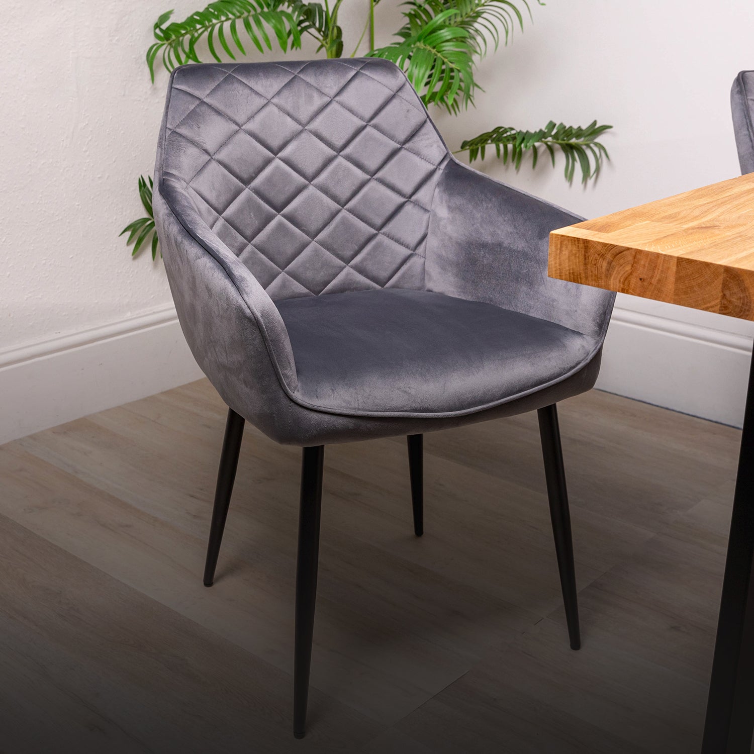 Storm grey velvet chair in a room with a solid oak wooden table and plants.