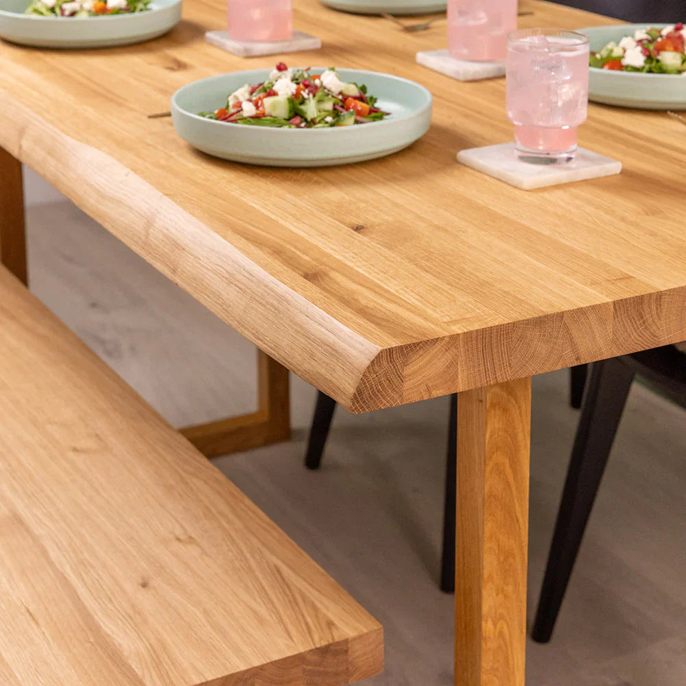 Solid oak dining table with a natural waney edge, set for everyday dining.