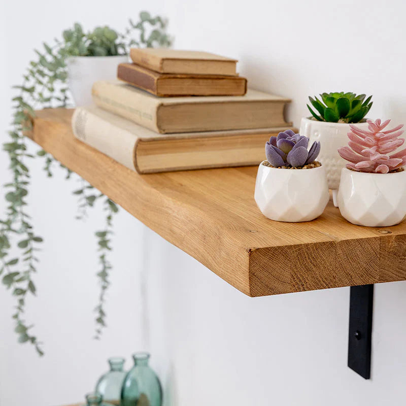 Solid oak live edge wall shelf with visible grain, styled with books and potted plants.