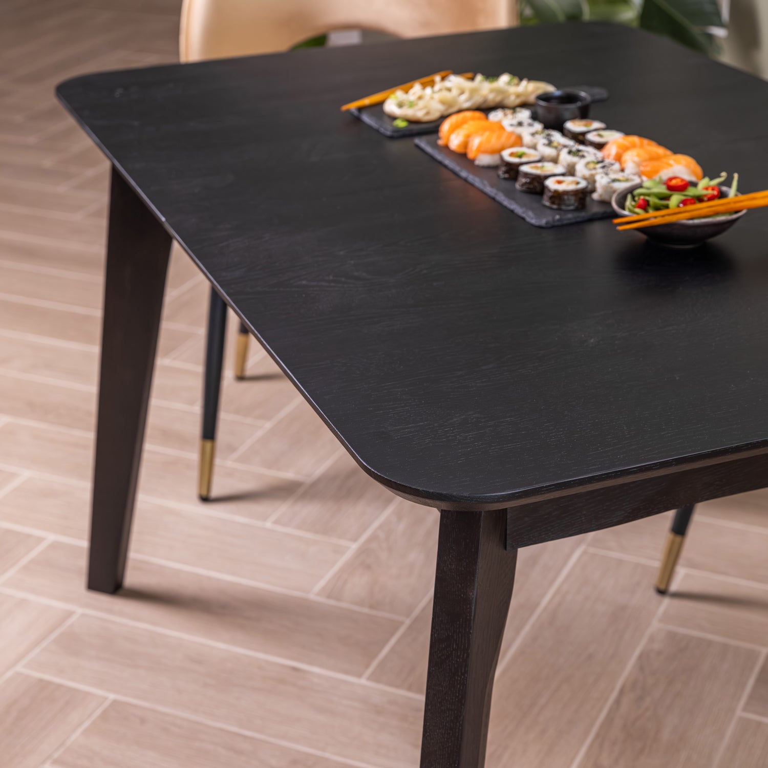 A modern rectangular extendable black dining table with shown in a dining room setting with sushi plates on top.