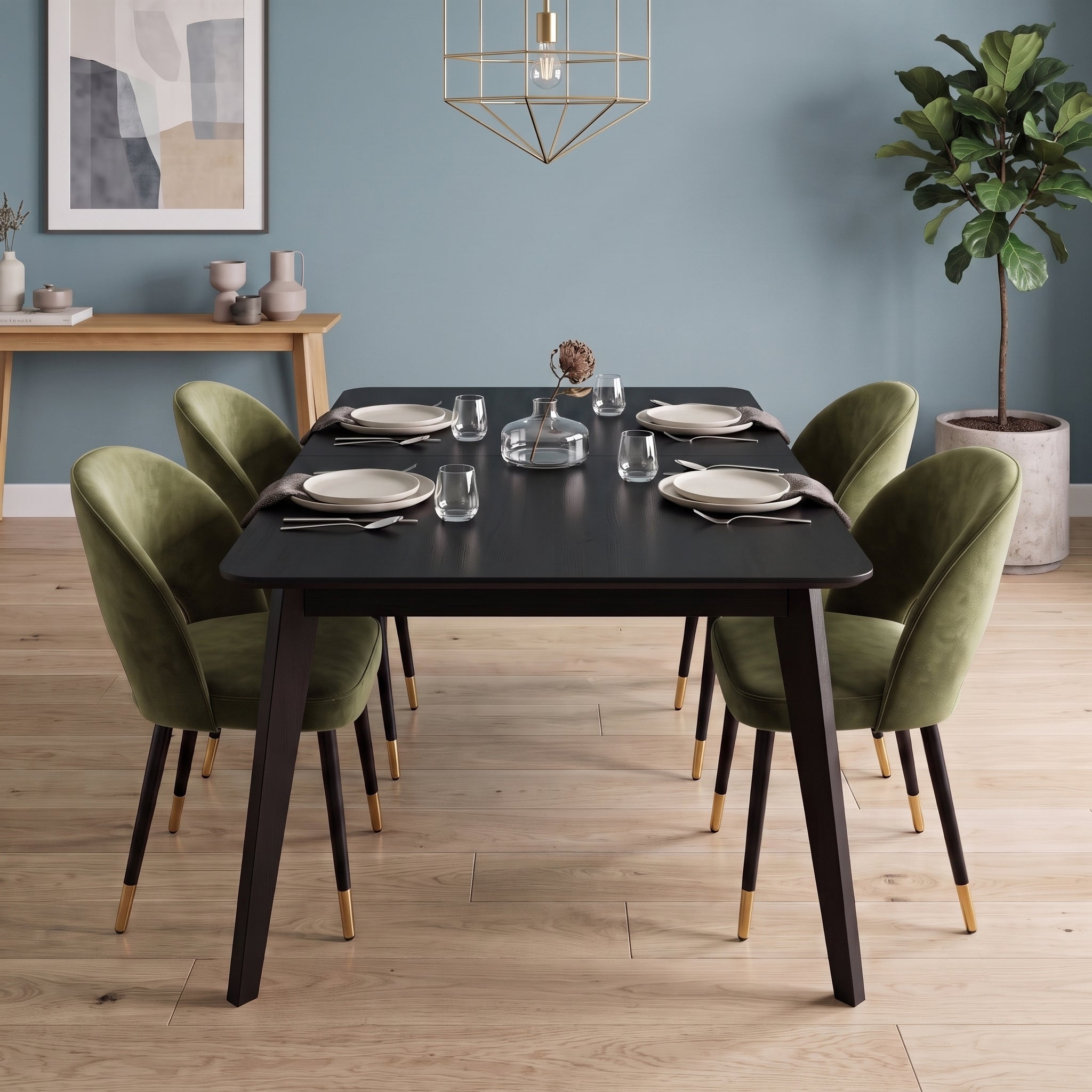 A modern dining room scene featuring a rectangular black table with dark legs and four olive green velvet chairs with champagne-toned leg caps, set on a light wood floor against a blue wall.