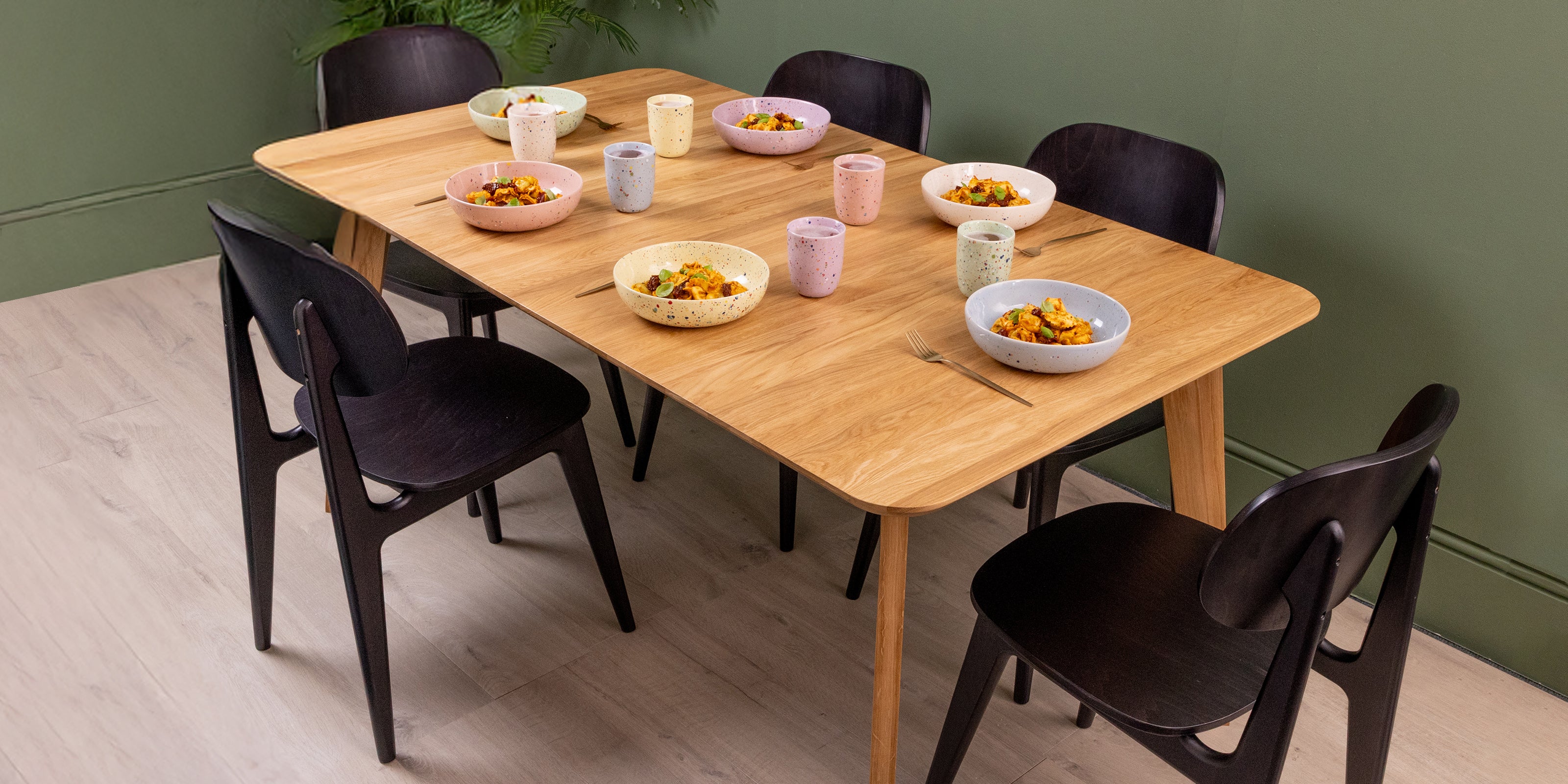 Extendable solid oak dining table with black chairs, set for everyday dining.
