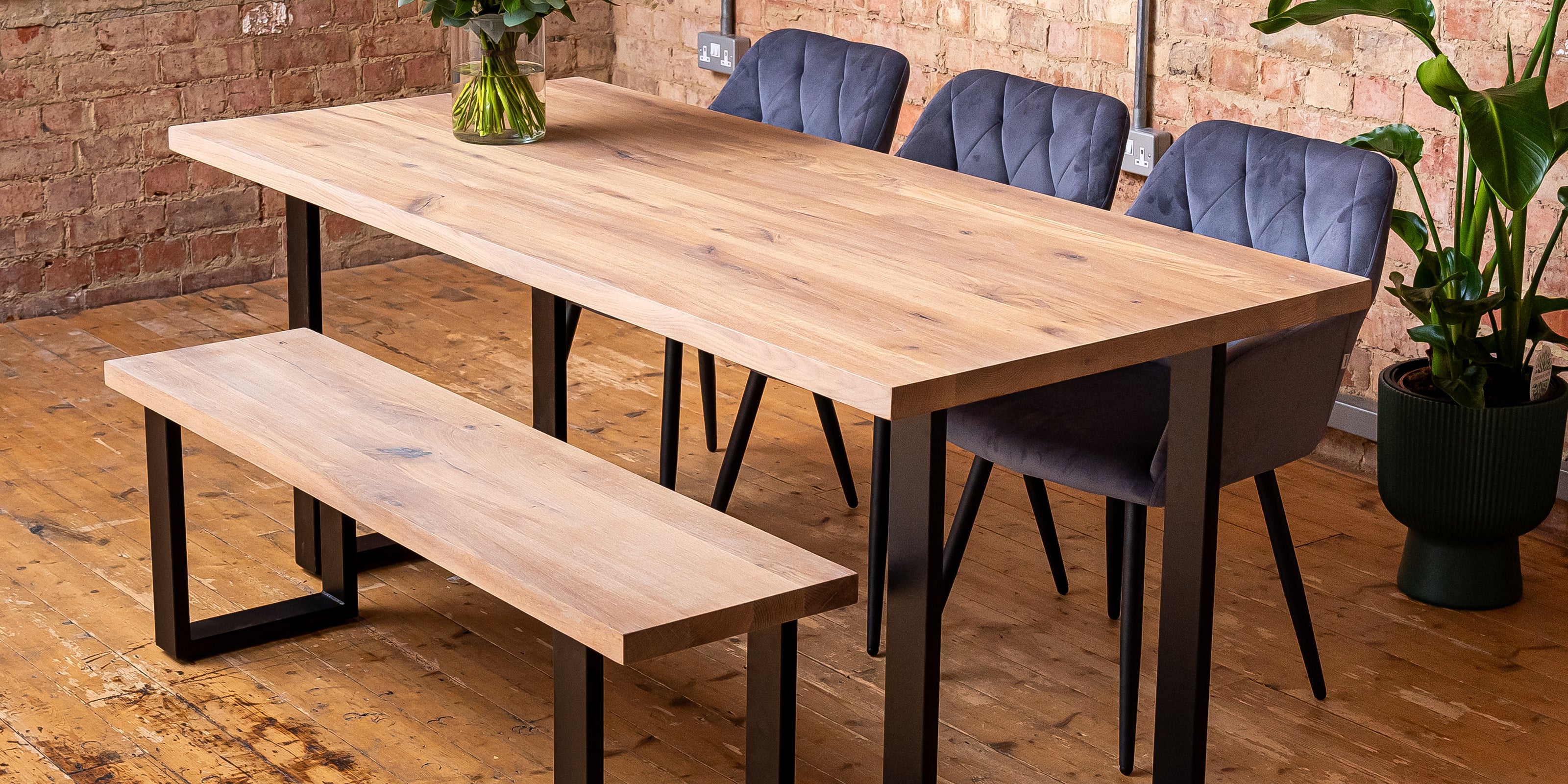 Premium oak dining table in natural light oak finish with blue velvet chairs and a solid oak bench.