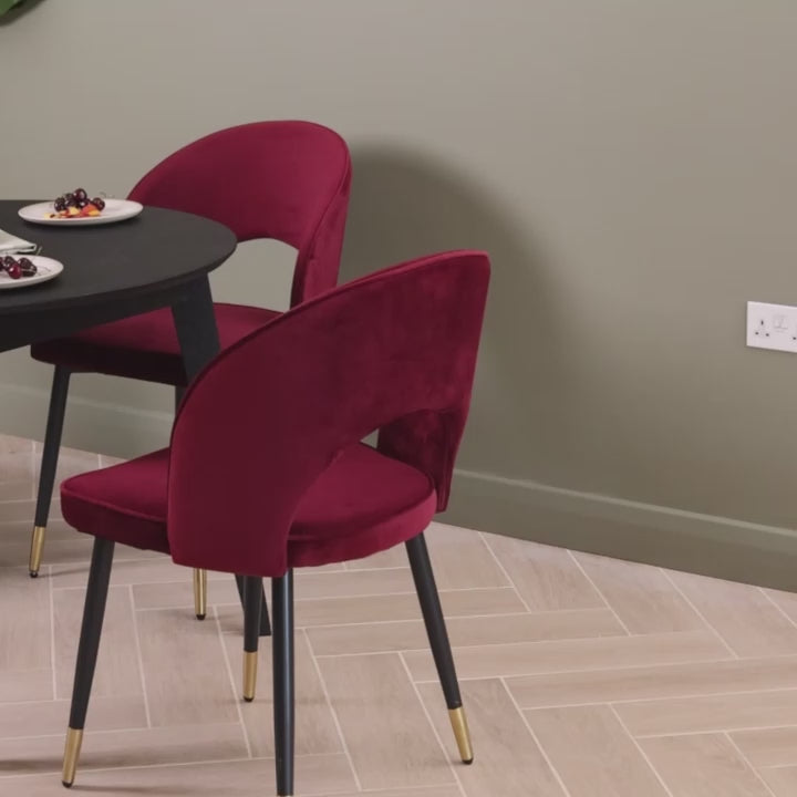 Video of a solid oak round extendable dining table finished in black, featuring 4 oxblood velvet dining chairs.