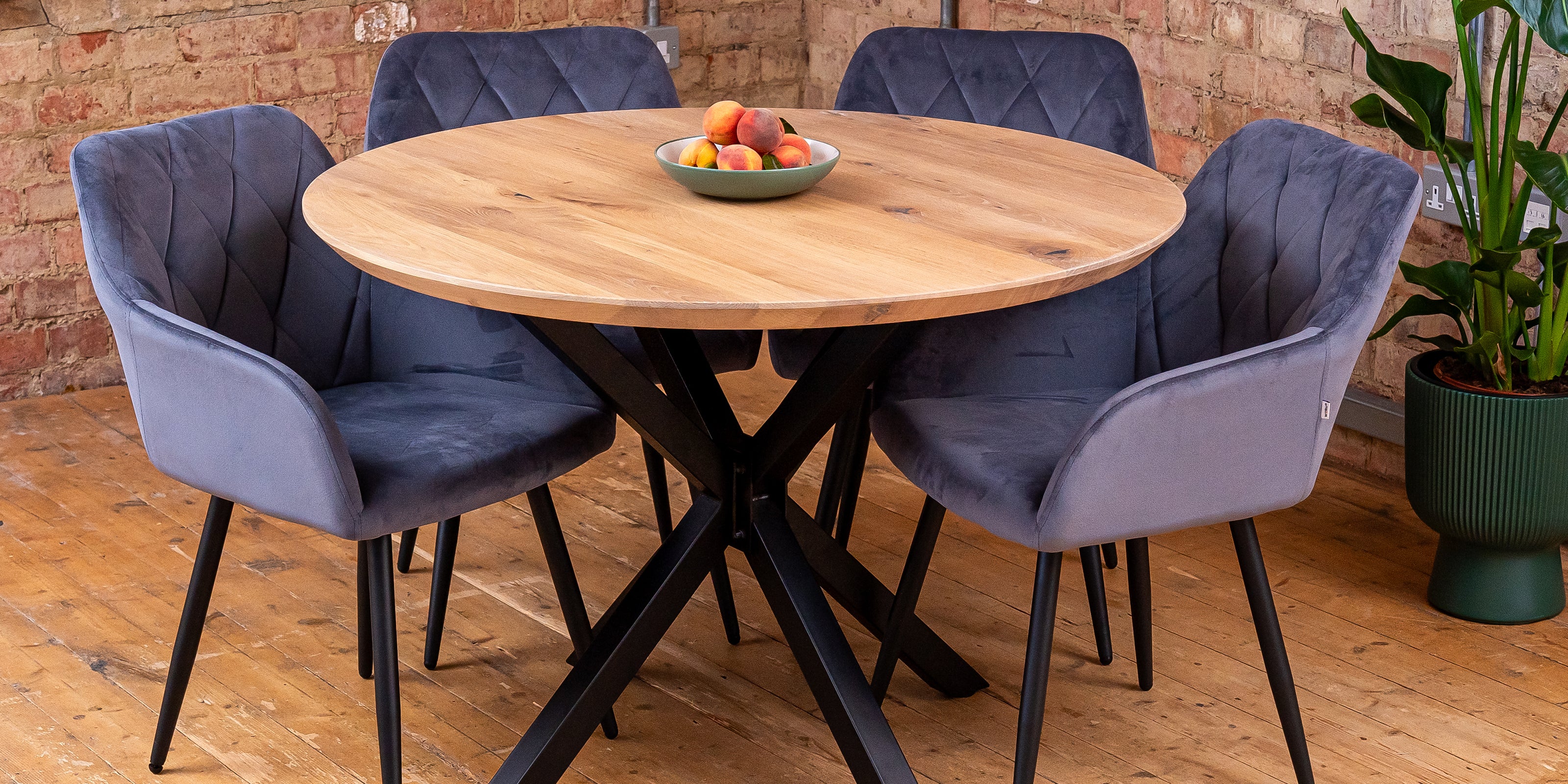Round solid oak dining table with black spider-style base, paired with dining chairs.