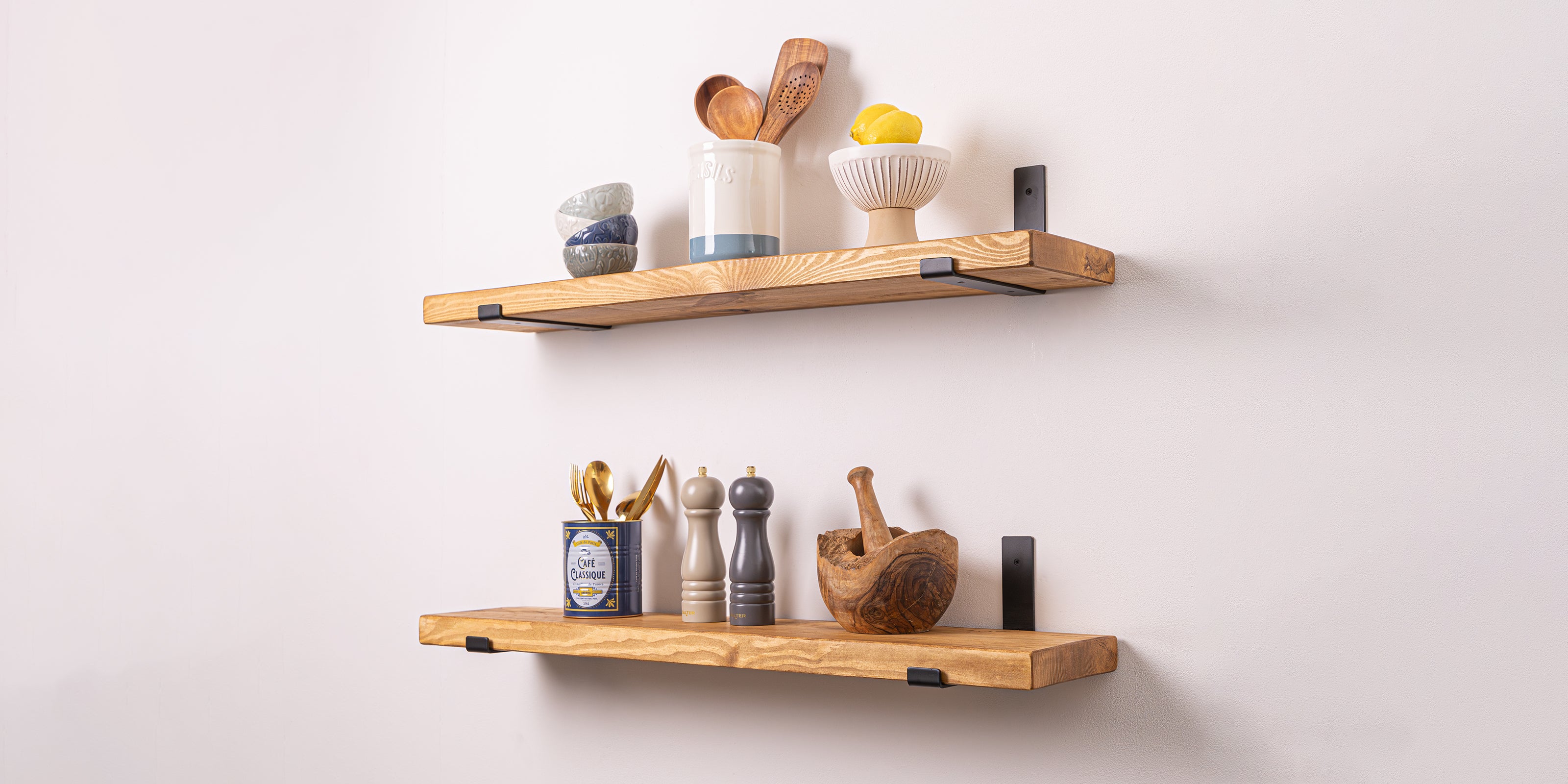 Two rustic pine shelves with kitchen items on a white wall