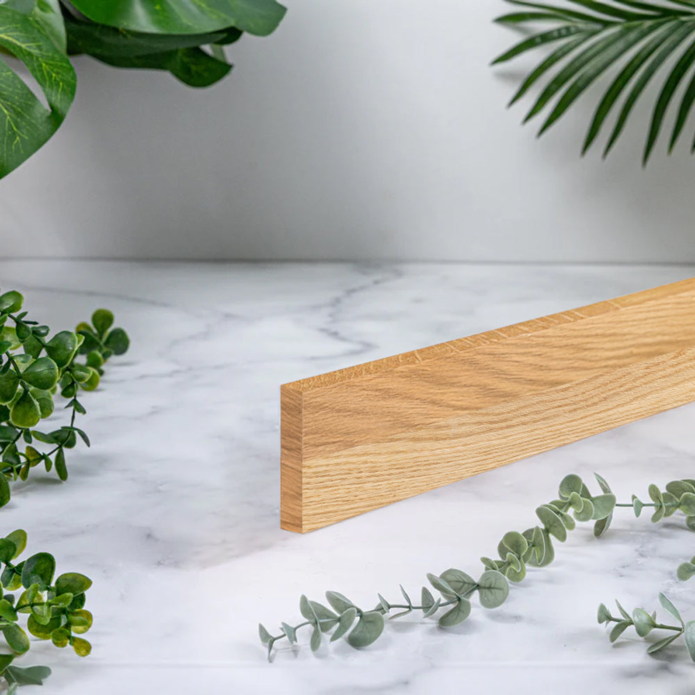 A full stave solid oak worktop upstand with 40mm wide staves, photographed on a white marble surface with green plants around it.