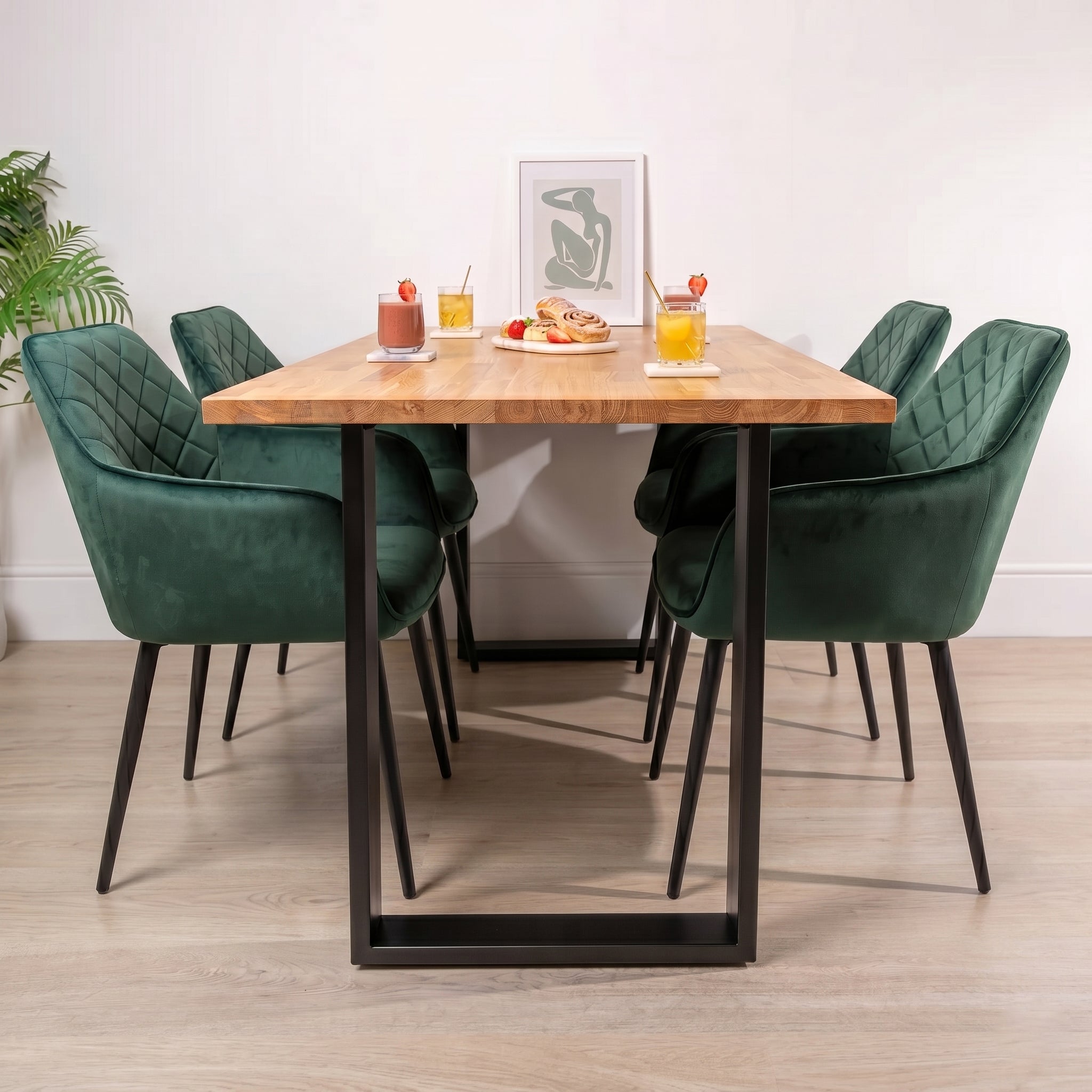 Dining table with four green chairs and a small plant in the corner.