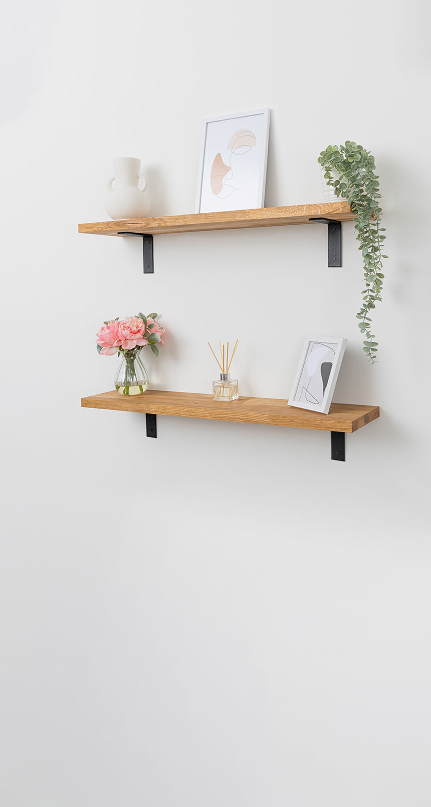 A pair of solid oak wall shelves accessorised with picture frames, plants and vases.
