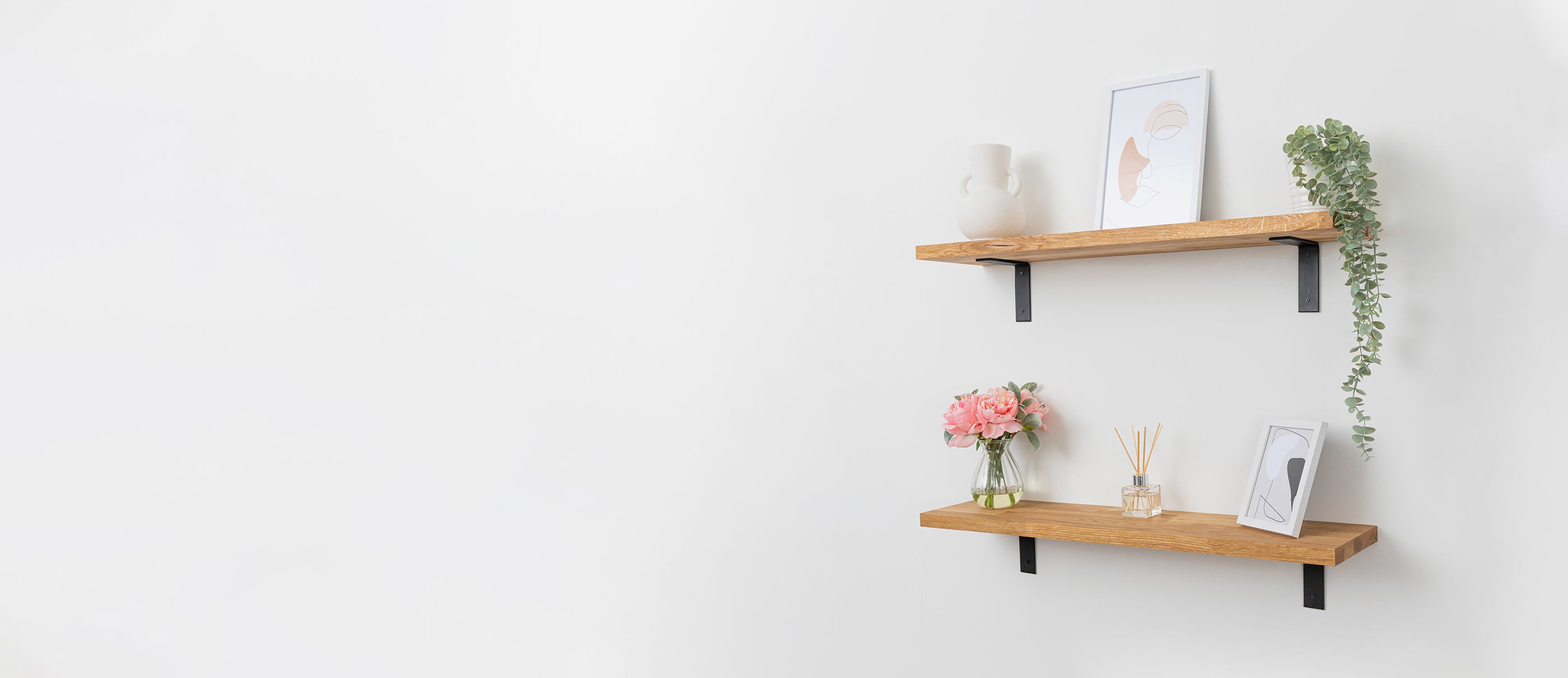 A pair of solid oak wall shelves accessorised with picture frames, plants and vases.