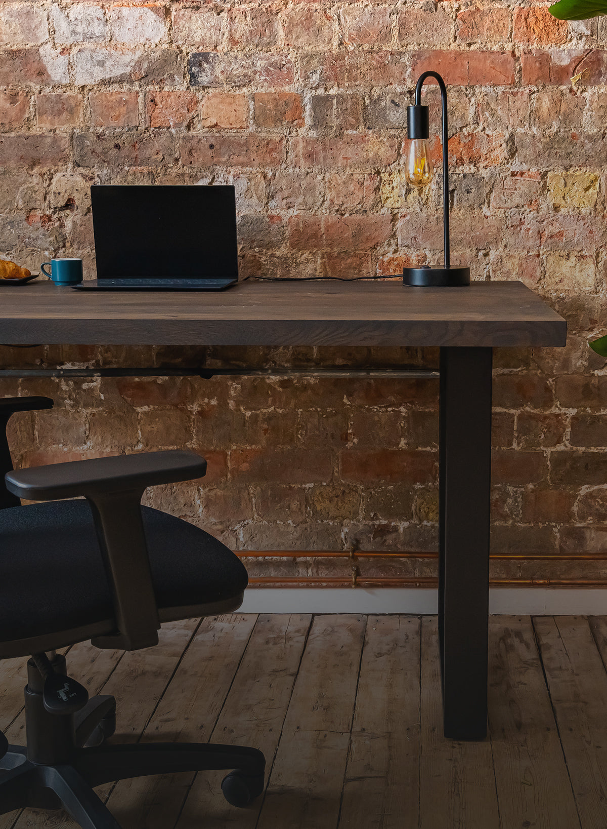 Solid wood desk shown in a natural office setting with chair.