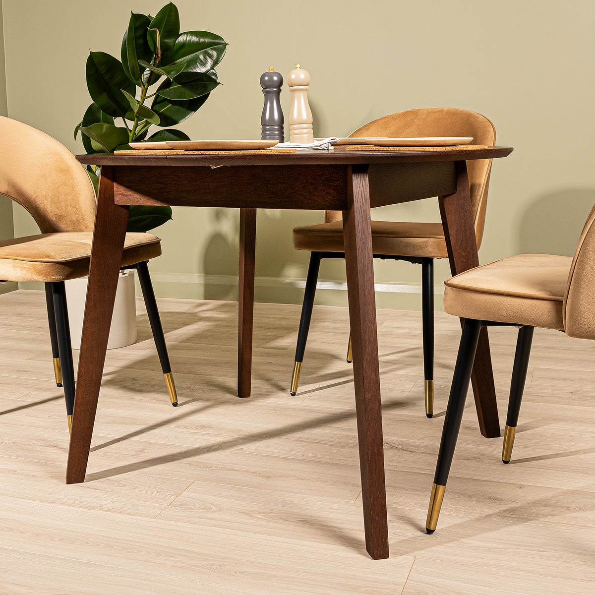 A modern oak extendable dining table in walnut finish with three upholstered chairs in a styled dining room setting with a light wood floor and sage green walls.