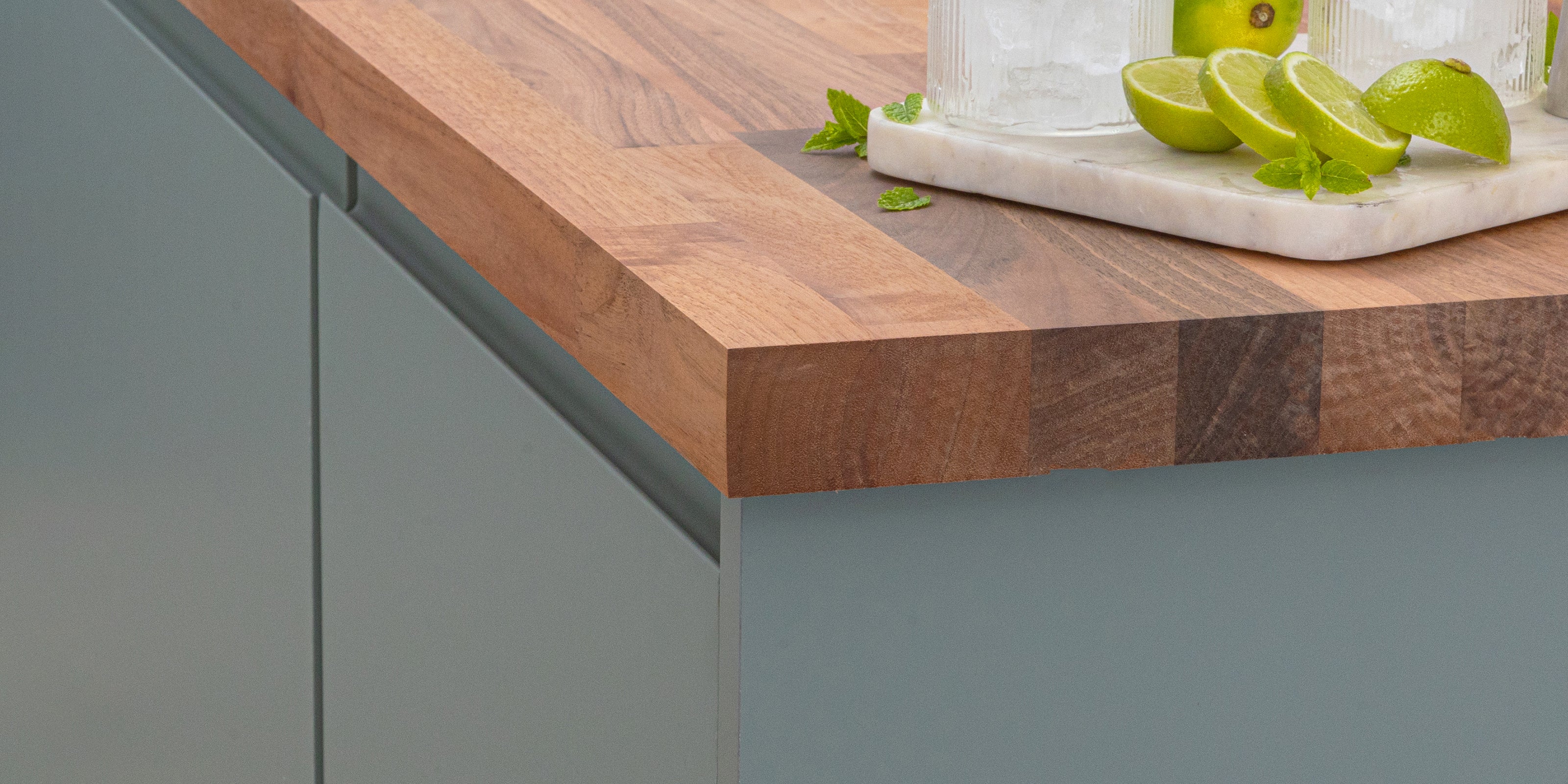 Walnut worktop edge showing natural grain detail on a painted kitchen cabinet.